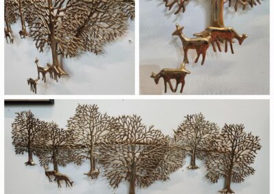 Metal wall art featuring deer and trees in a natural woodland scene.