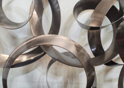 Abstract wall art with overlapping metallic rings in bronze and silver tones.