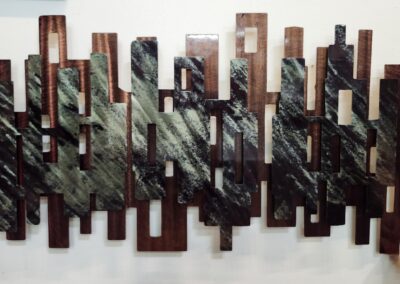 Modern metal wall art with abstract geometric design in black and copper tones.