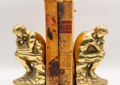 Gold thinker bookends holding two old books upright.