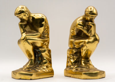 Two golden sculptures inspired by Rodin's The Thinker.
