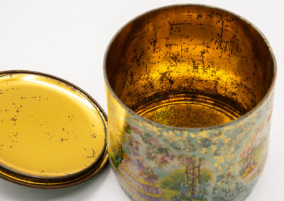 Close-up of a vintage metal container with a lid, showing aged patina.
