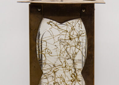 Artistic sculpture featuring a white torso with abstract gold lines inside a rustic frame.