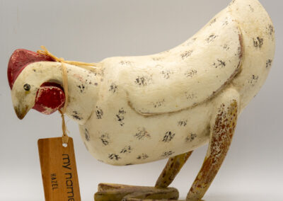A decorative wooden chicken with intricate patterns and a small tag.