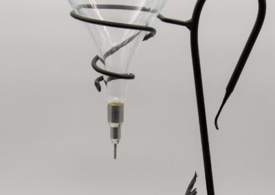 A black metal hook stand holding a clear glass funnel with a spiral design.