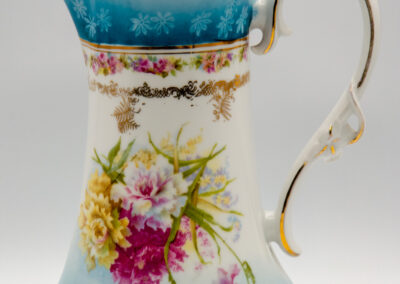 Elegant porcelain pitcher with floral design and gold accents.