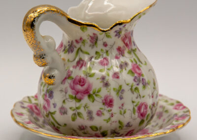 Elegant floral porcelain pitcher with matching saucer and gold accents.