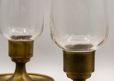 Close-up of two vintage brass candle holders with glass chimneys.