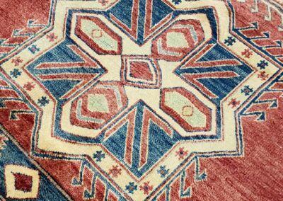 Intricately patterned geometric star design on a vintage red rug.