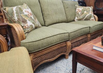 Elegant green upholstered sofa with carved wooden frame and floral cushions.