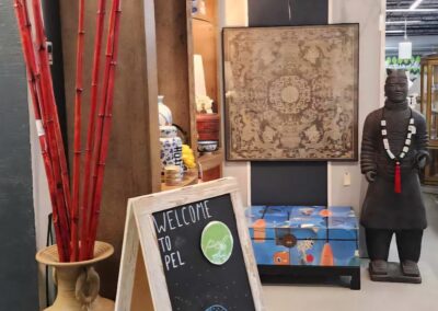 Art gallery corner with sculptures, paintings, and a chalkboard sign.