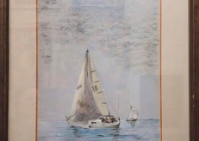 A sailboat glides peacefully on calm waters under a cloudy sky.
