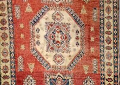 Intricately patterned red and beige oriental rug with central medallion and floral motifs.