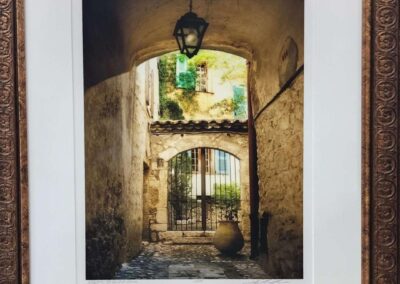 A rustic arched passageway with an old lantern and greenery beyond.