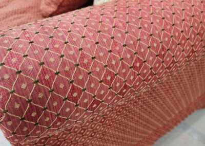 Close-up of a textured, patterned pink fabric on a cushion.