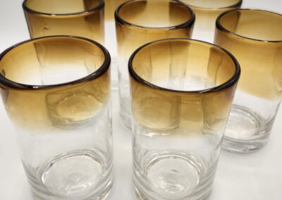 Set of seven clear glasses with brown gradient tops arranged closely.