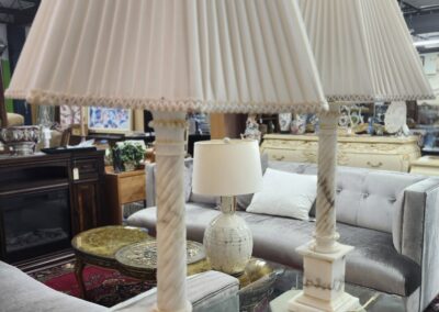 Pair of elegant cream-colored table lamps with pleated shades on a glass table.