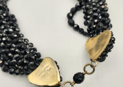A close-up of a multi-strand black beaded necklace with gold-toned clasps.