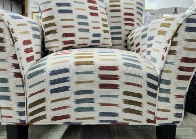 Modern armchair with multicolored striped upholstery and dark wooden legs.