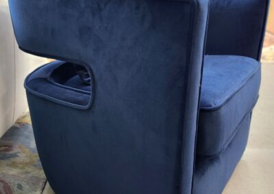 Modern navy blue velvet armchair with a sleek, open side design.