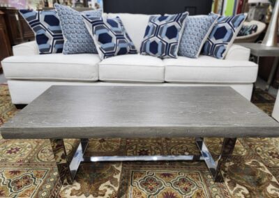 Wooden coffee table with a dark finish in front of a white couch with patterned pillows.