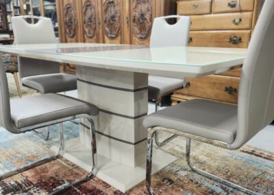 Modern dining table with cushioned chairs in a stylish room.