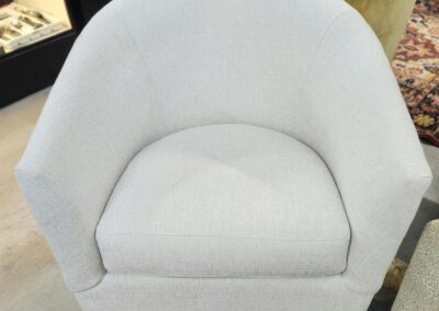 A modern white upholstered armchair with a curved backrest.