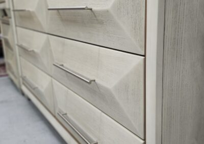 Close-up of modern light-colored drawer handles on a wooden dresser.