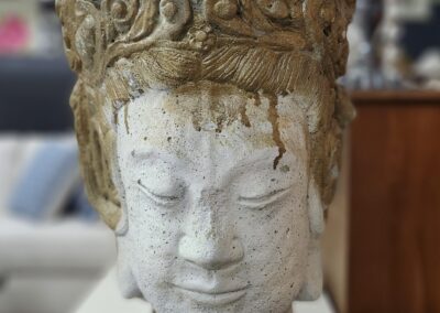 Close-up of a serene stone Buddha head statue with intricate crown details.