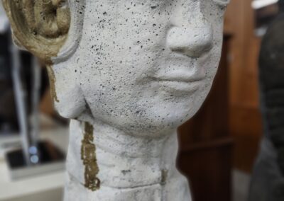 Close-up of a serene stone Buddha statue with detailed facial features and dangling earrings.