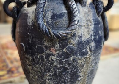 Ancient ceramic amphora with rope handles and aged surface.