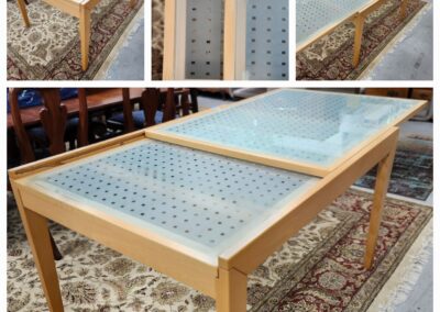 A wooden display table with a glass top on a patterned carpet.