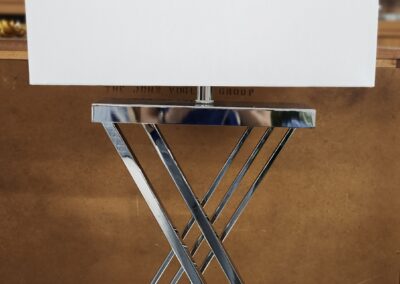 Modern table lamp with a white rectangular shade and chrome X-shaped base.