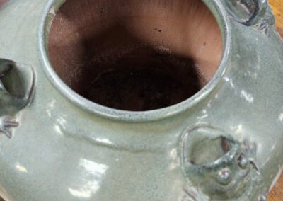 Close-up of a ceramic jar with a wide opening and decorative elements.