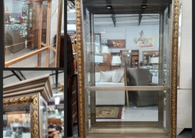 Large ornate gold-framed mirror in a store with various items reflected.