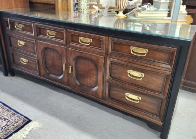 Elegant wooden cabinet with brass handles and a dark marble countertop.