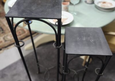 Two nested metal tables with wooden tops in a dining setting.