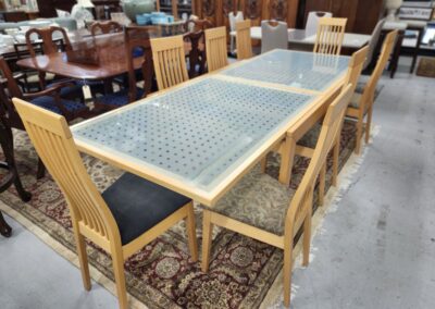 Wooden dining table with six matching chairs in a showroom.