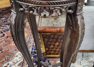 Ornate wooden pedestal table with intricate floral carvings and curved legs.