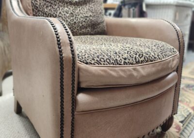 A stylish brown armchair with leopard print cushions and nailhead trim.