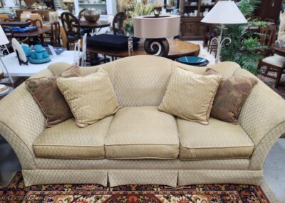 A beige upholstered sofa with four cushions in a living room.