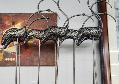 Metal flamingo sculptures arranged in a row with bent necks.