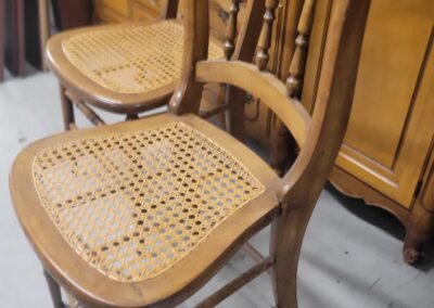 Vintage wooden chairs with woven cane seats and decorative backs.