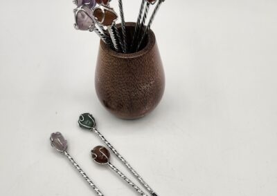 Handcrafted floral hairpins displayed in a wooden vase and on a white surface.