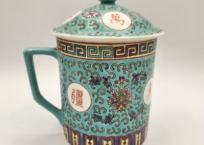 Ornate ceramic mug with lid featuring intricate Asian-inspired patterns and symbols.