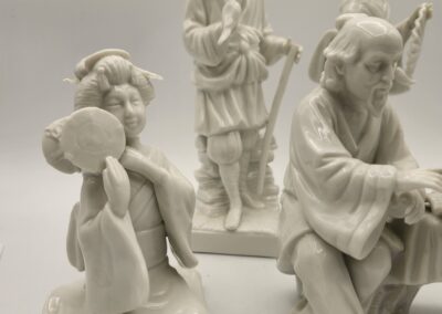 Three white porcelain figurines depicting traditional Asian musicians and dancers.