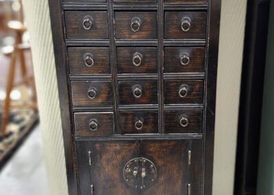 Antique wooden cabinet with multiple small drawers and a larger compartment at the bottom.