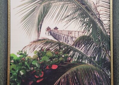 A tropical scene with palm leaves and red flowers under a cloudy sky.