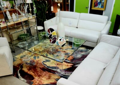 Modern living room with white sofas and a colorful glass coffee table.