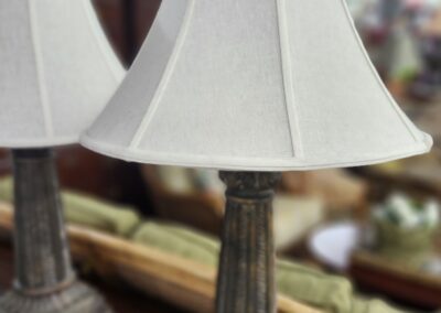 A rustic table lamp with a beige shade on a wooden surface.